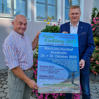 Bild vergrößern: NaturEinKlang 2022 - Das Bild zeigt den Veranstalter Karl-Heinz Karmann (links) mit Erstem Bürgermeister Rudolf Seidl bei der Plakatvorstellung vor dem Rathaus in Maxhütte-Haidhof.