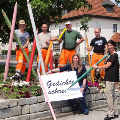 Bild vergr��ern: Das Bild zeigt Erste B�rgermeisterin Dr. Susanne Plank beim �Schreiben� der ersten Buchstaben mit Mitarbeiterin Anita Alt, die ihr das Blatt festh�lt zusammen mit den Kreativen des G�rtner-Trupps vom st�dtischen Bauhofes (von links) Birgit Graf, Dieter Sch�berl, Stefan Haslinger und Thomas Roidl, welche f�r die dekorative Begleitidee zust�ndig waren.