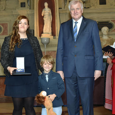 Bild vergr��ern: Das Bild zeigt Vanessa Rieger mit ihrem geretteten, kleinen Bruder Jesaja und Ministerpr�sident Horst Seehofer nach der �berreichung der Rettungsmedaille.